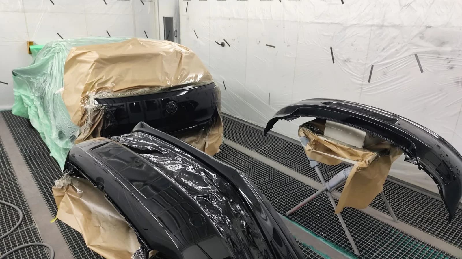 Hayon de Volkswagen Polo et pare-chocs noirs fraîchement peints en cabine, le reste du véhicule sous bâche