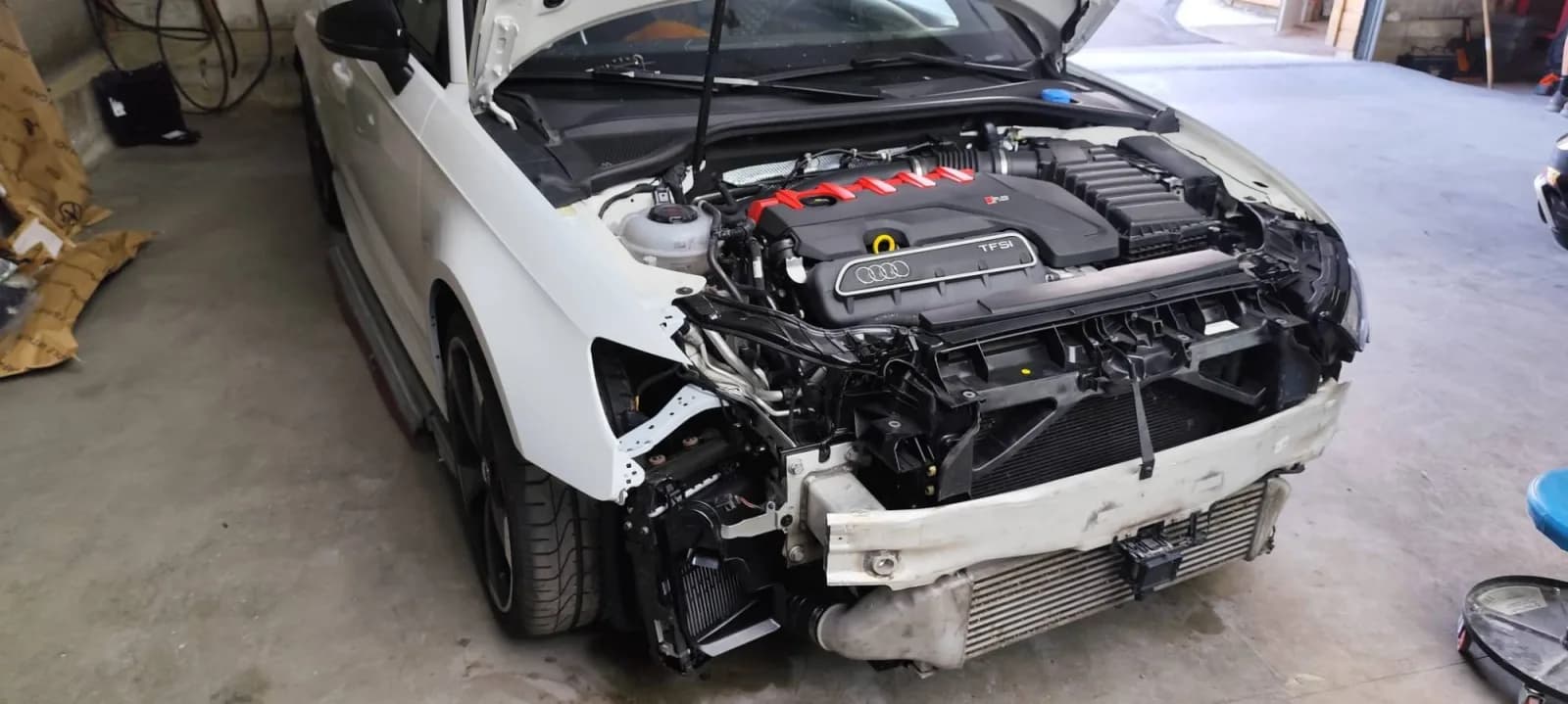 Audi RS 3 blanche à l'avant entièrement déposé : pare-chocs, optique et aile retirés, traverse, radiateurs et échangeur apparents