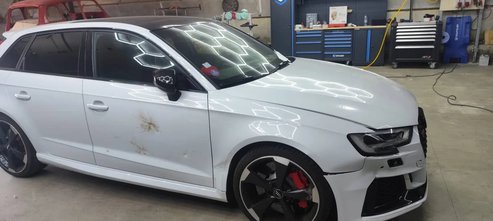 Audi RS 3 blanche avant réparation, aile et porte avant droite marquées, pare-chocs désaligné à l'aile