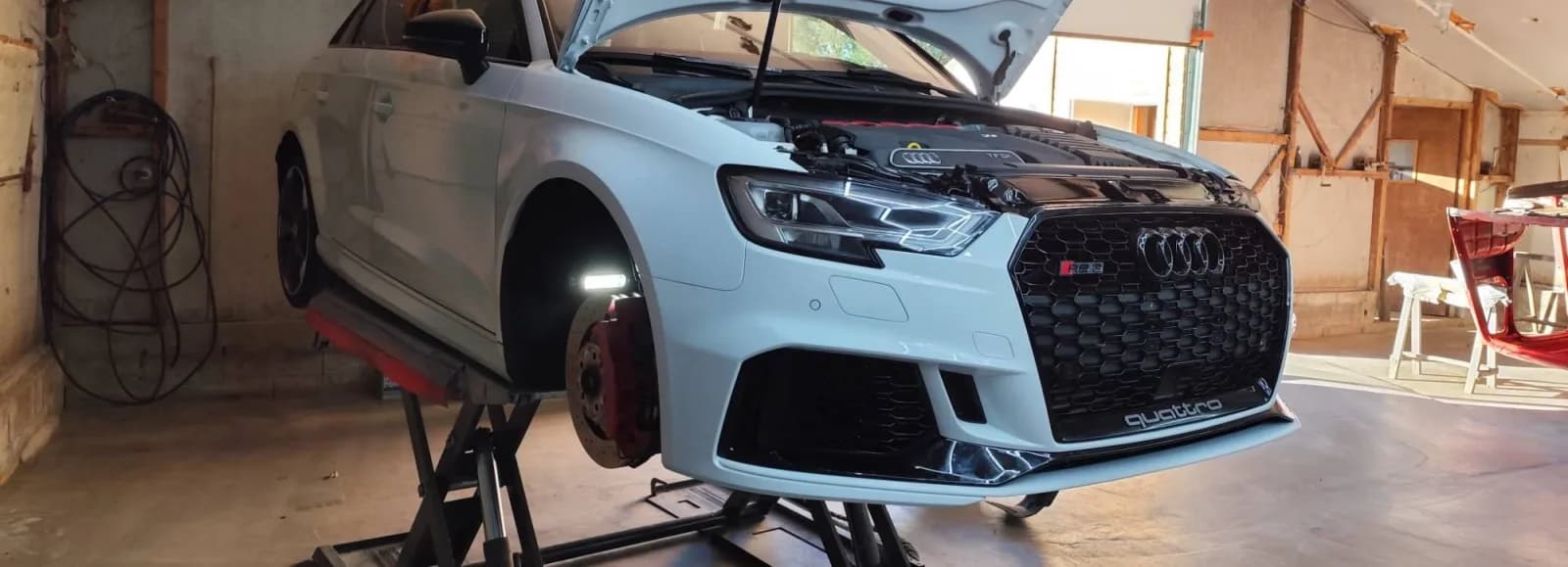 Audi RS 3 levée sur pont élévateur, avant remonté avec pare-chocs, calandre et optique en place, capot ouvert