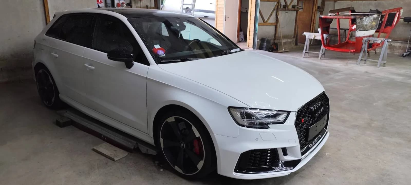 Audi RS 3 Sportback blanche terminée dans l'atelier, avant remonté, vue de trois quarts